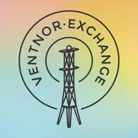 The logo for  The Ventnor Exchange. A black line drawing of a radio tower inside a circle with the words 'VENTNOR. EXCHANGE' around the top half of the circle, on a rainbow gradient background.