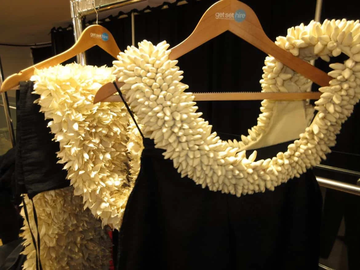 Clothes featuring a garment with a large floral collar made of white flowers.