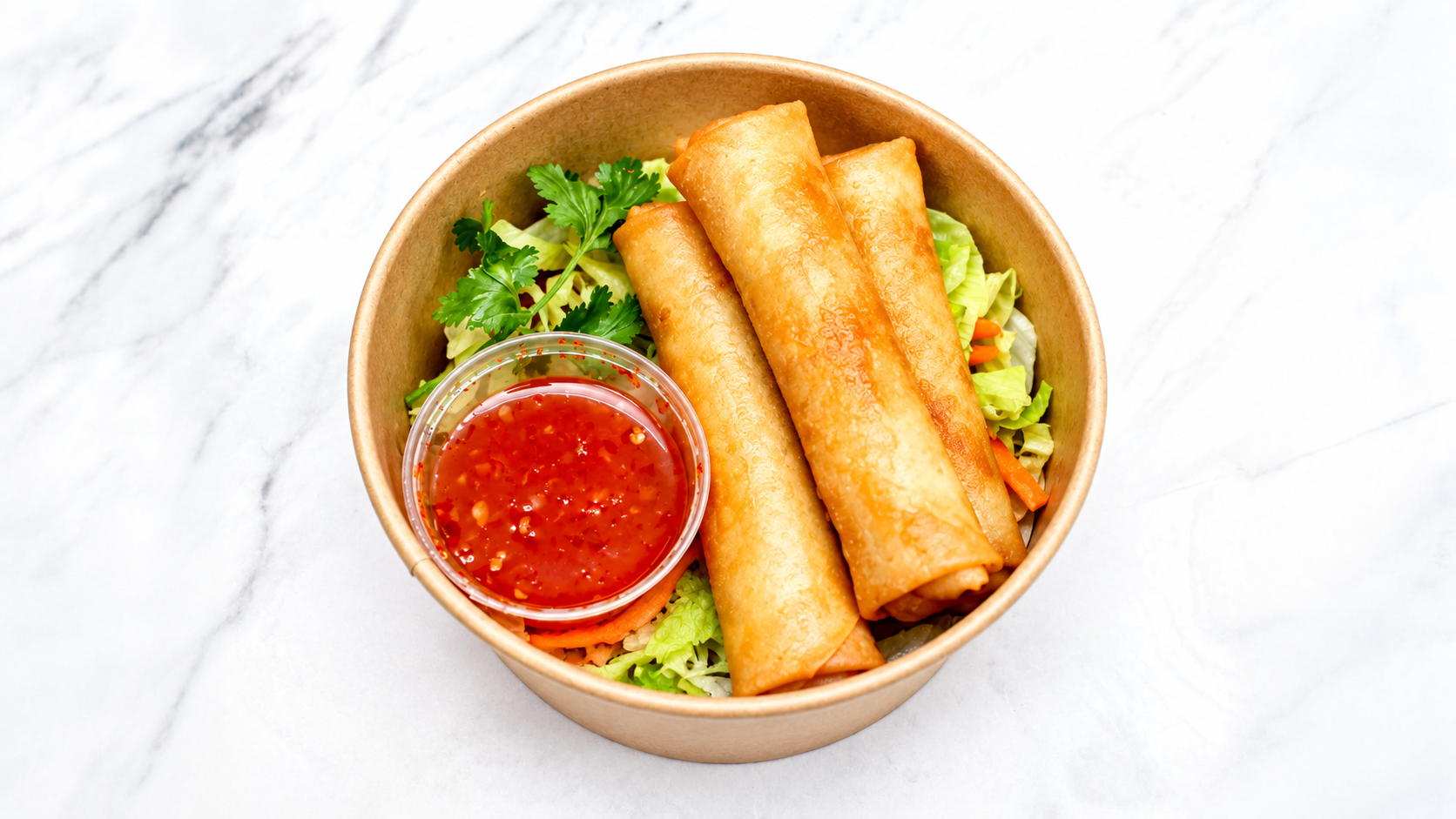 Three fried spring rolls with a side of red dipping sauce and a small garnish of cilantro in a paper bowl on a white marble surface.