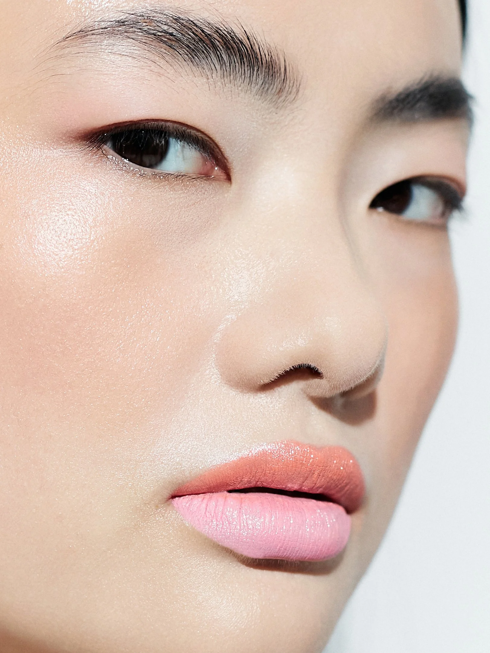 Close-up of a woman's face focusing on her eye, eyebrow, cheeks, and lips with makeup.