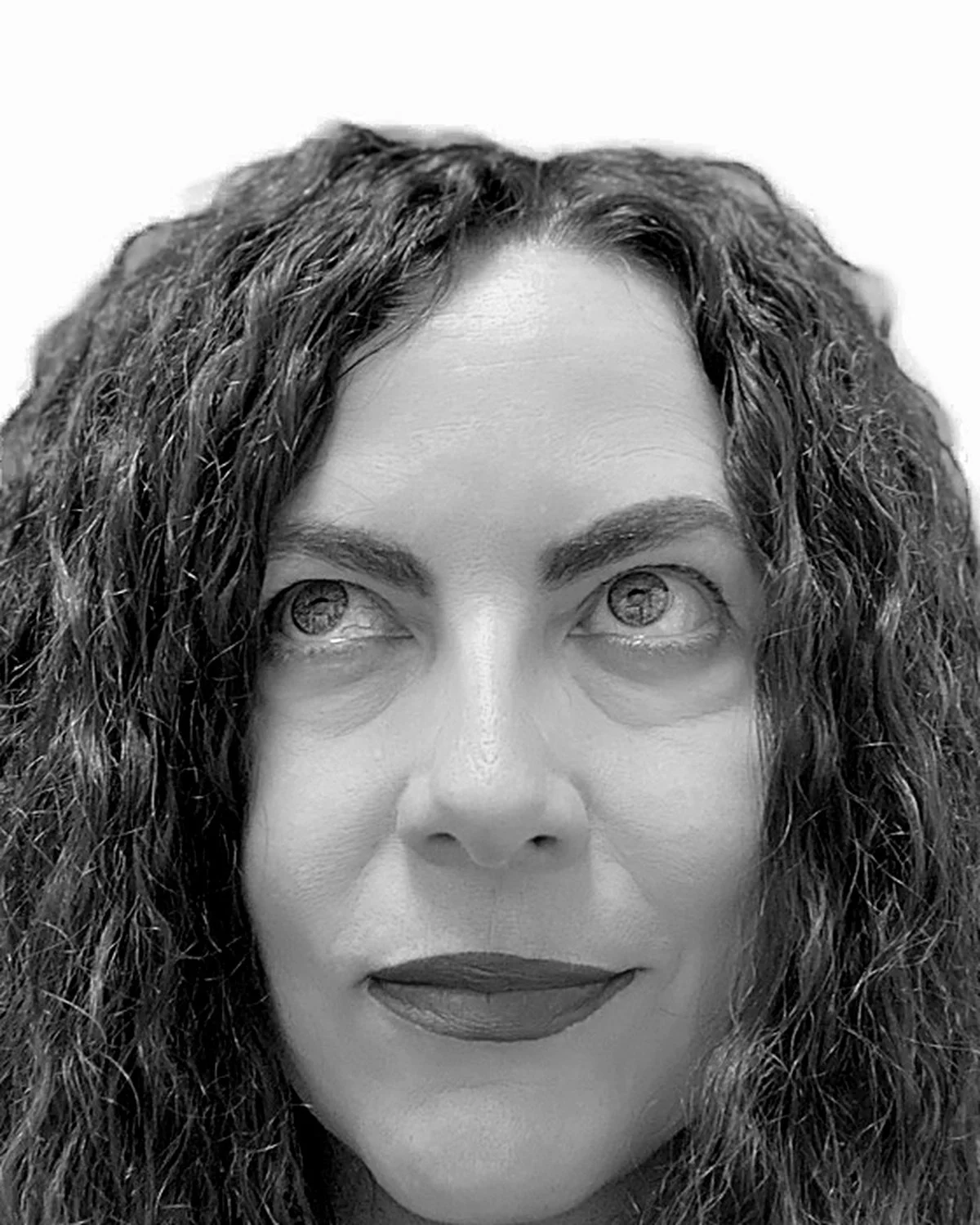 Close-up black and white photo of a woman's face with curly hair, looking upwards with her eyes, eyebrows, and lips visible.