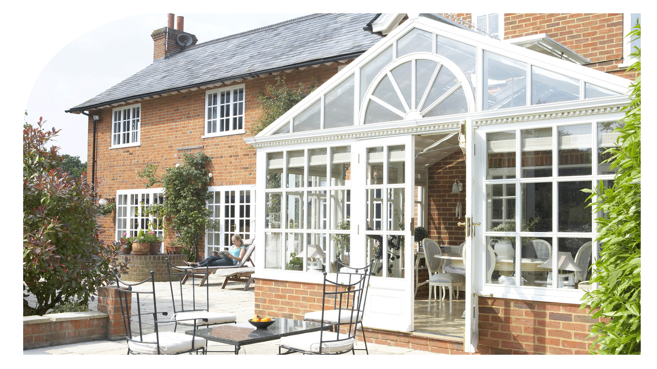 A brick house with a glass conservatory and an outdoor patio.