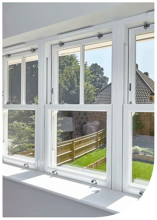View through white-framed windows showing a backyard with a green lawn, a wooden fence, and trees in the background.