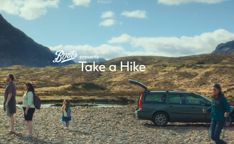 Group of people hiking near a parked car in a mountain landscape with a clear sky.