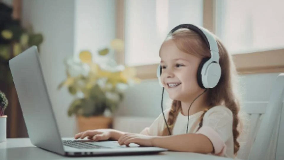 Smiling young girl wearing headphones and using a laptop at home