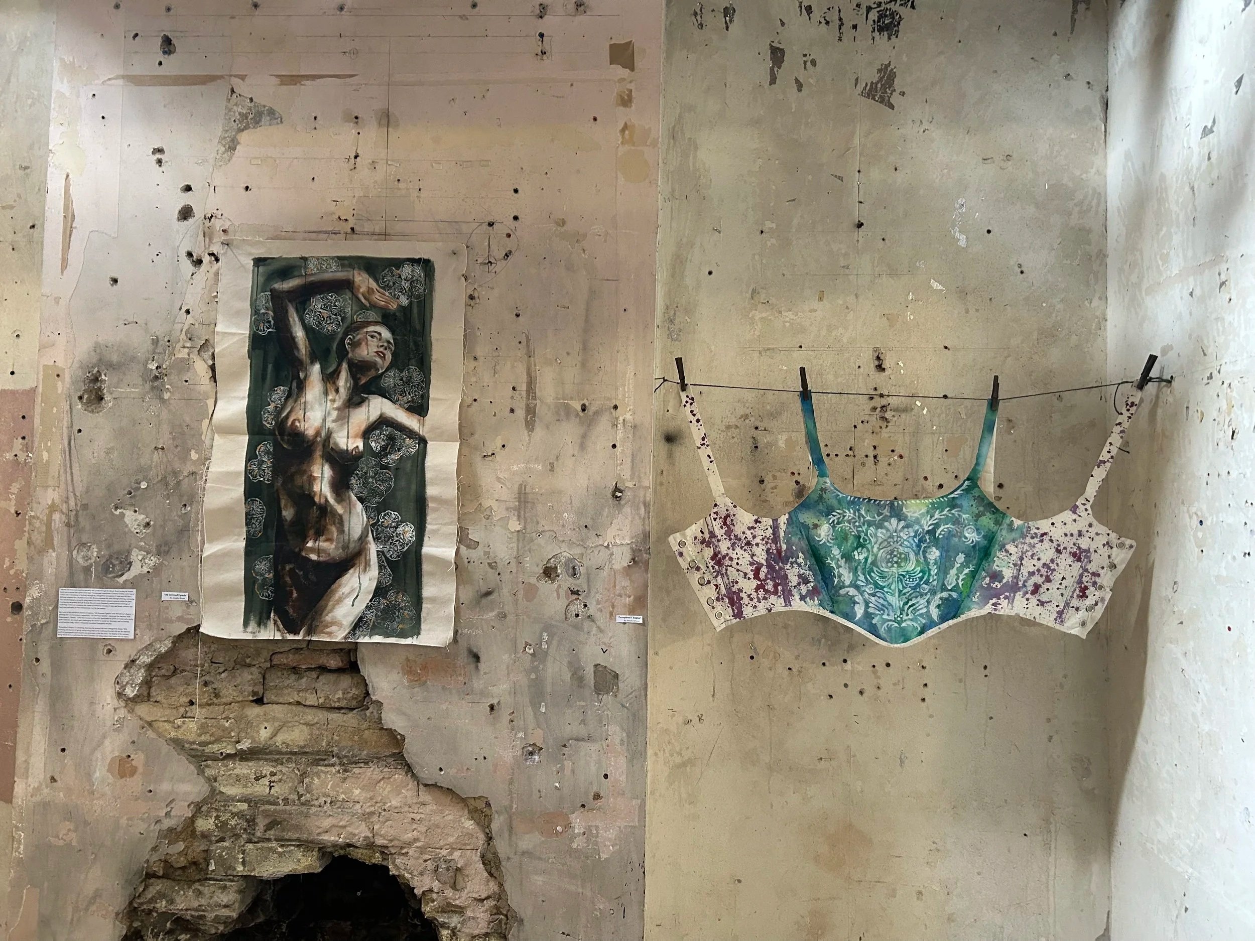 A peeling wall with a painting of a woman with dark hair and a blue dress hanging on it. The wall shows signs of damage with holes, cracks, and peeling paint, and a section of brickwork is visible at the bottom left.