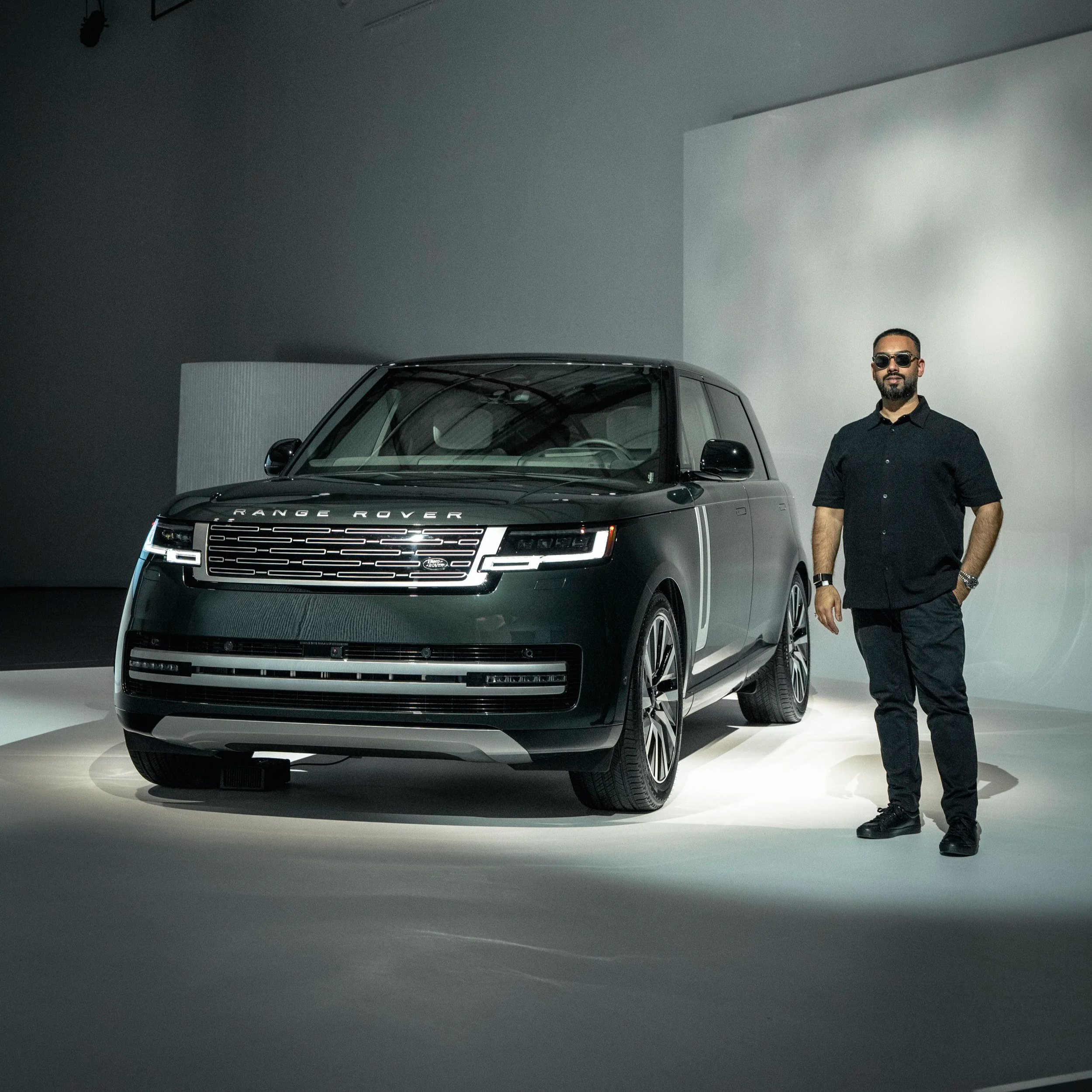 Range Rover
    EMKWAN standing beside a Range Rover electric in a modern indoor showroom.