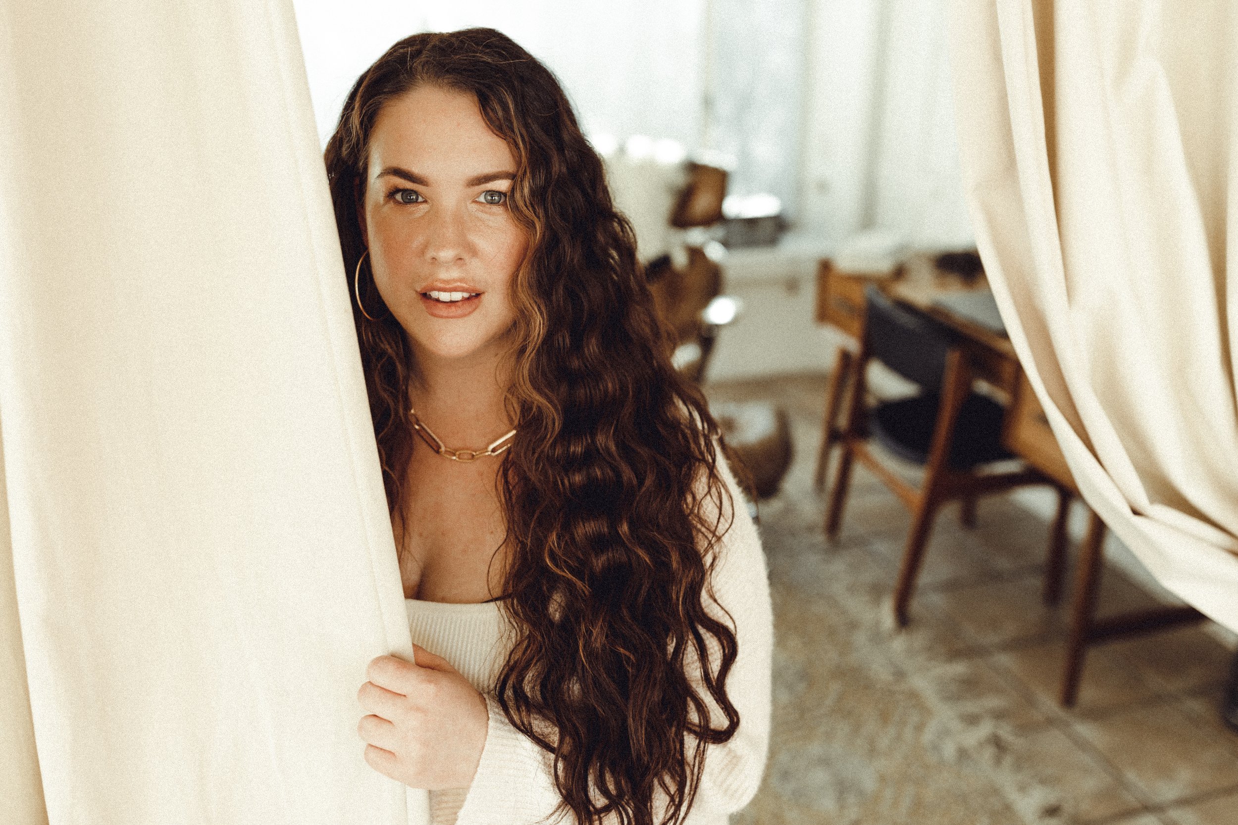 Melissa Jaramillo, Houston hairstylist and owner of Aloe Studio, with long brunette waves and gold jewelry. Wearing 24 inch extensions in a chocolate brunette color.