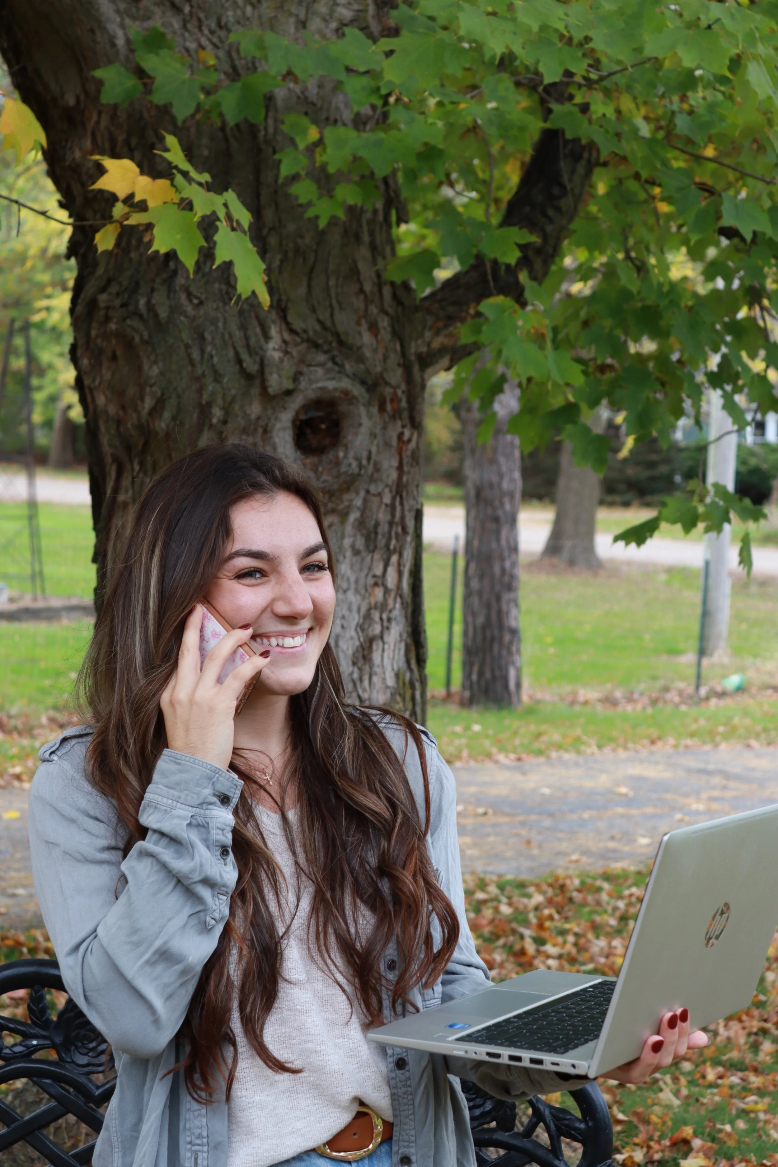 Olivia standing with her laptop, talking on the phone while smiling. SEO for small businesses can help owners reach clients who need your services. Learn more here!