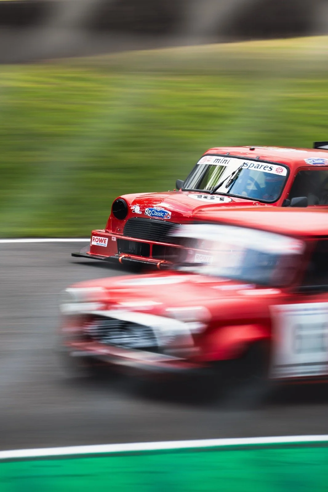 Red race car moving at high speed on a race track, with a blurred background and foreground indicating motion.