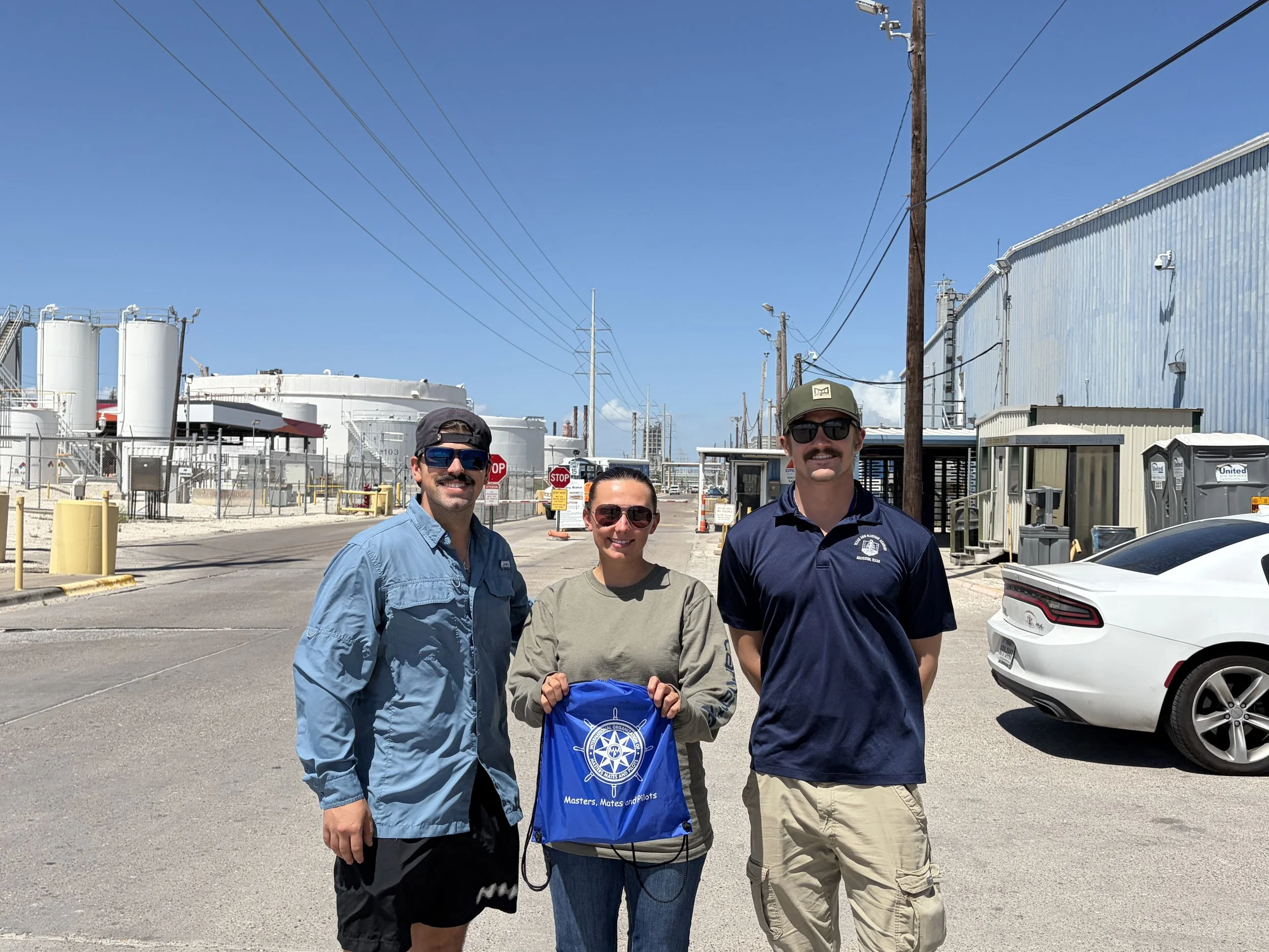 OSG Mates outside a port and industrial facility with storage tanks.