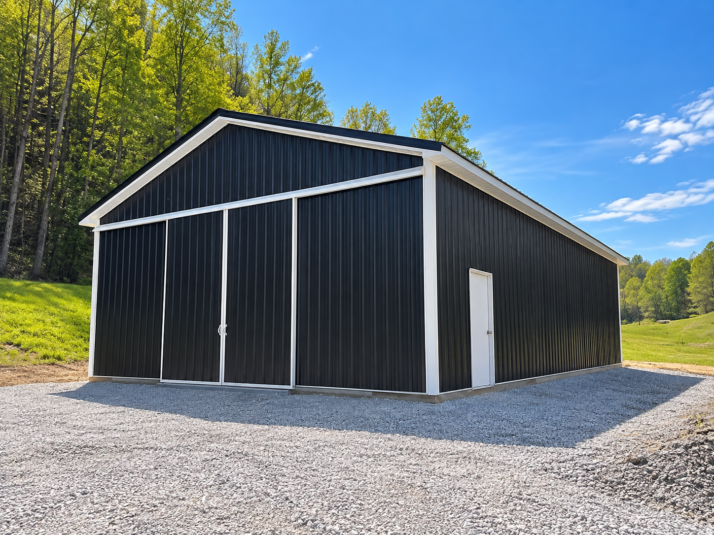 Black metal storage shed with white trim, two doors on the front and a side door, situated on a gravel lot surrounded by greenery and trees under a blue sky.