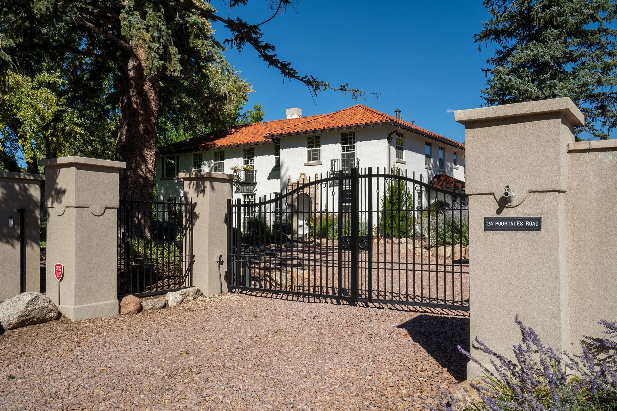 White stucco Spanish-style home with a red tile roof, gated courtyard, and stone walls at 24 Pourtales Road.