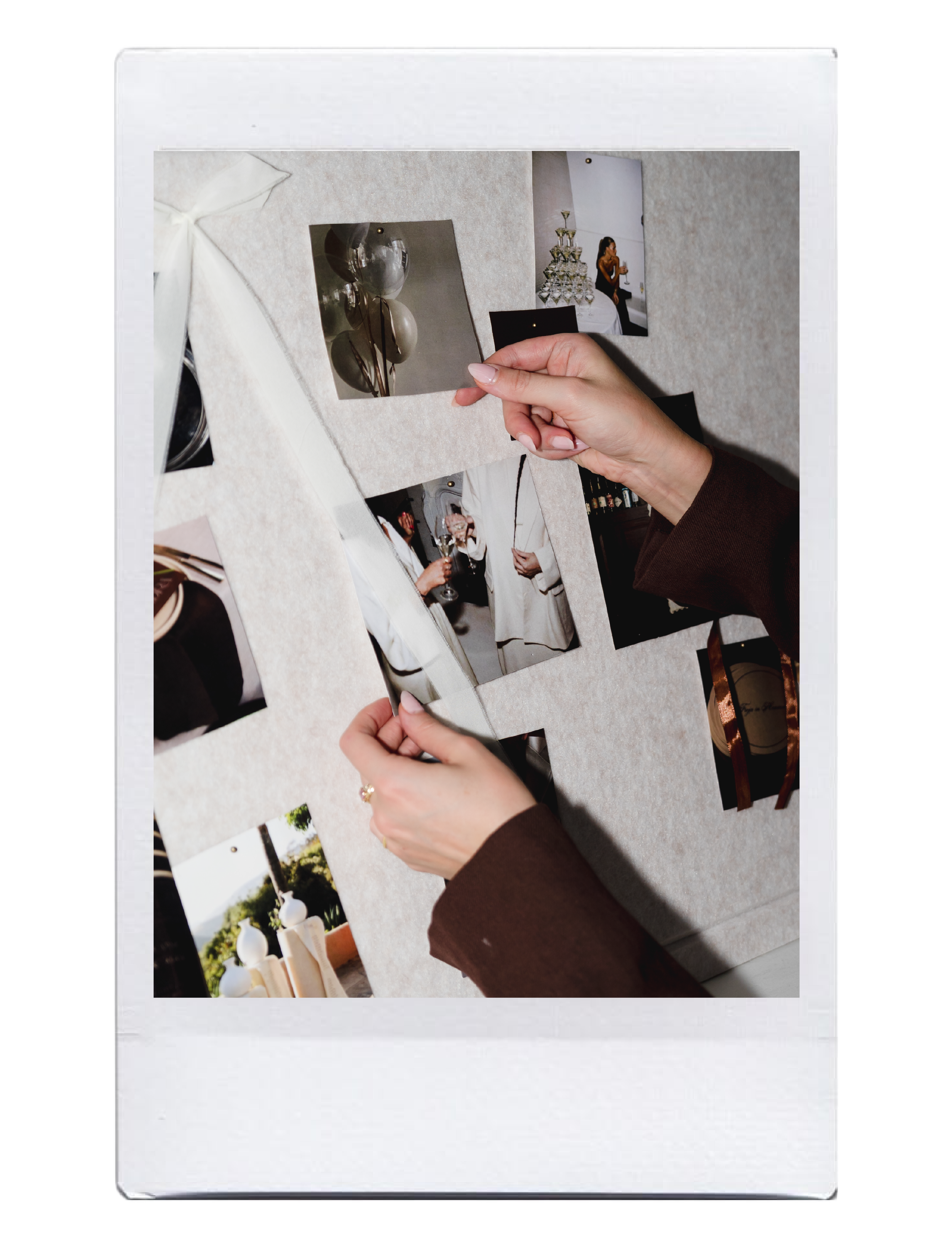 Photo of a collection of printed photographs and a person's hand holding one of the prints, displayed on a white table or surface.
