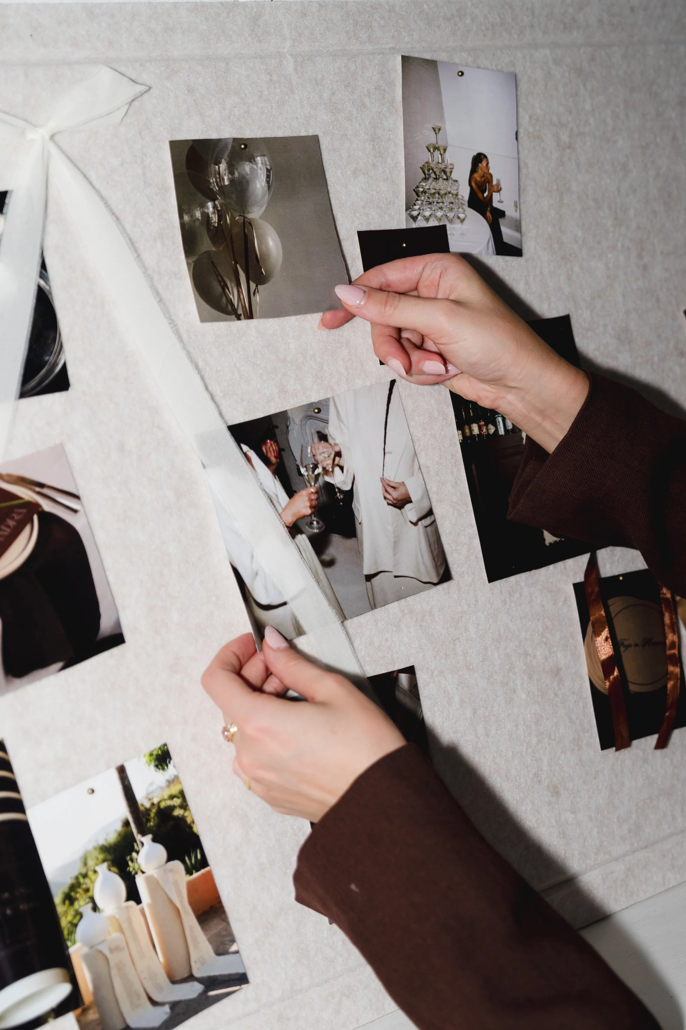 Close-up of hands holding photographs of balloon decorations and a woman drinking wine at a celebration.