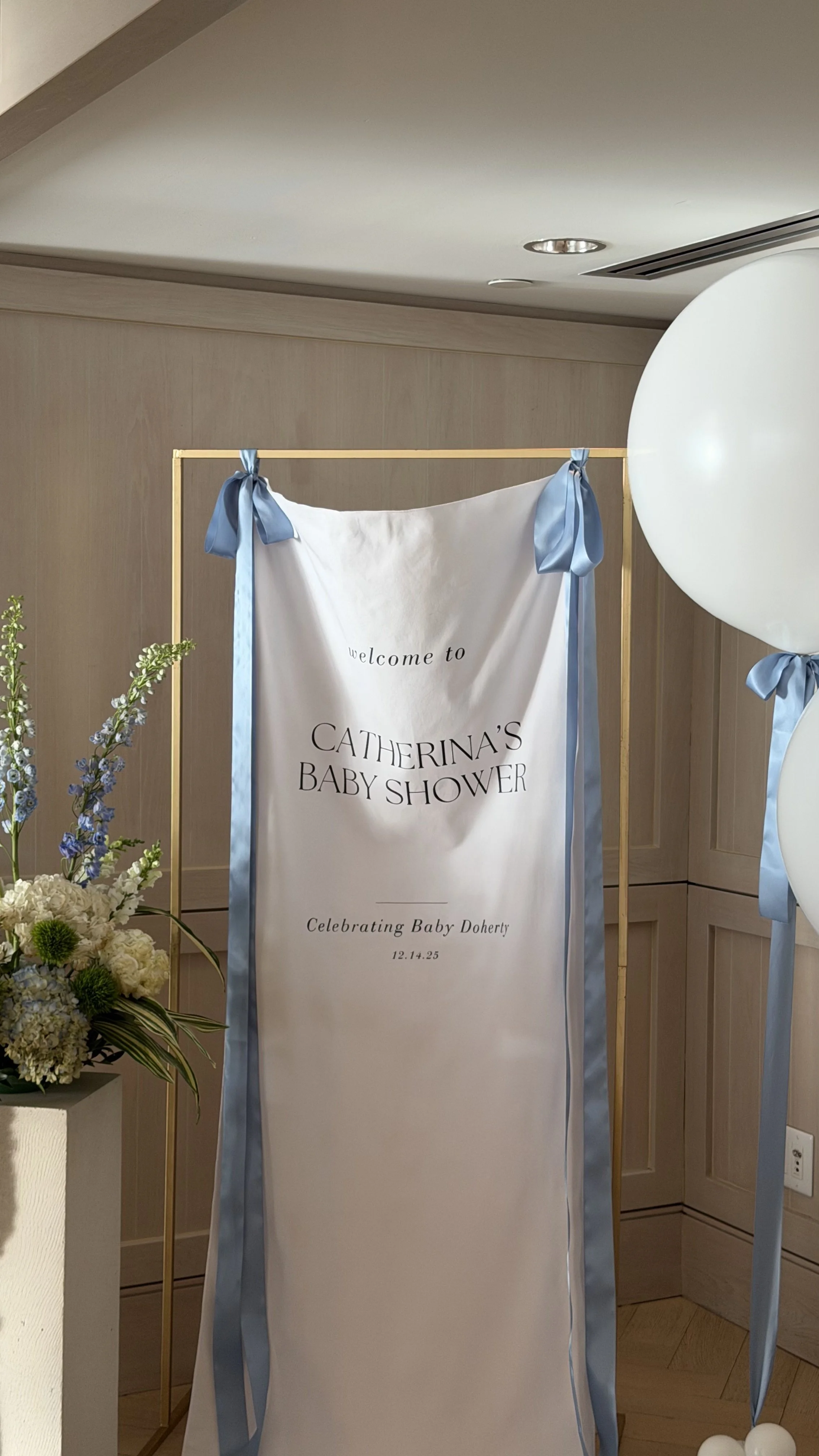 Invitation banner for a baby shower, with blue ribbons, celebrating a baby named Doherty, dated December 14, 2025.