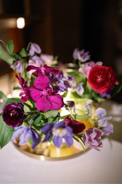Colorful mixed flower arrangement in a gold vase on a table.