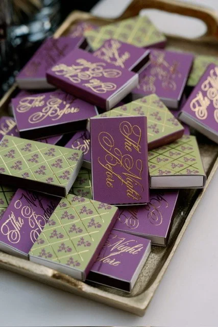 Small boxes of chocolates with purple and green packaging, some decorated with floral patterns, arranged on a tray.
