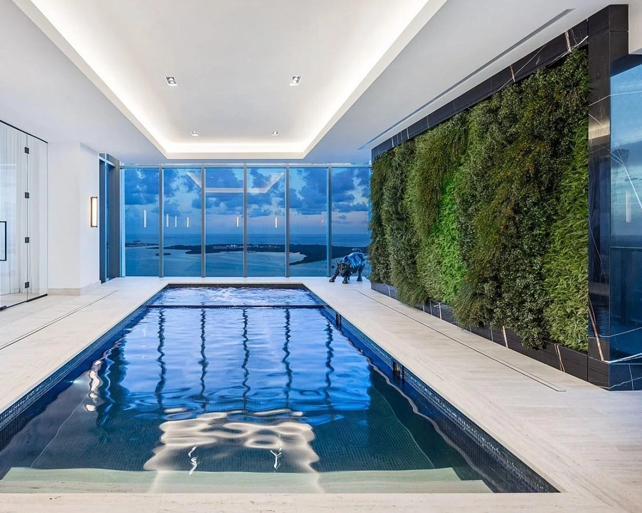 Indoor lap pool with a full-length greenwall and ocean view