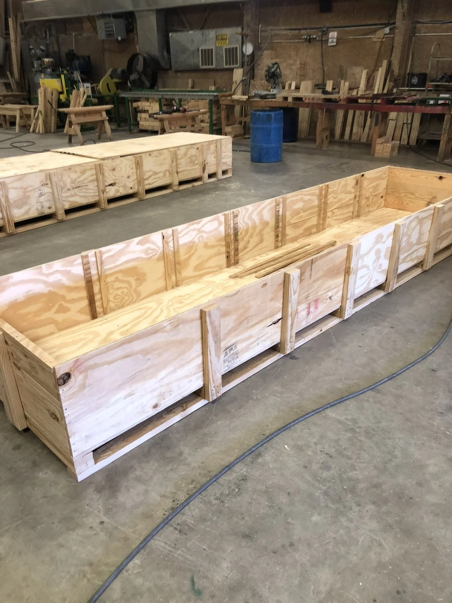 Workshop with unfinished wooden structures, workbenches, and various tools and materials for woodworking.