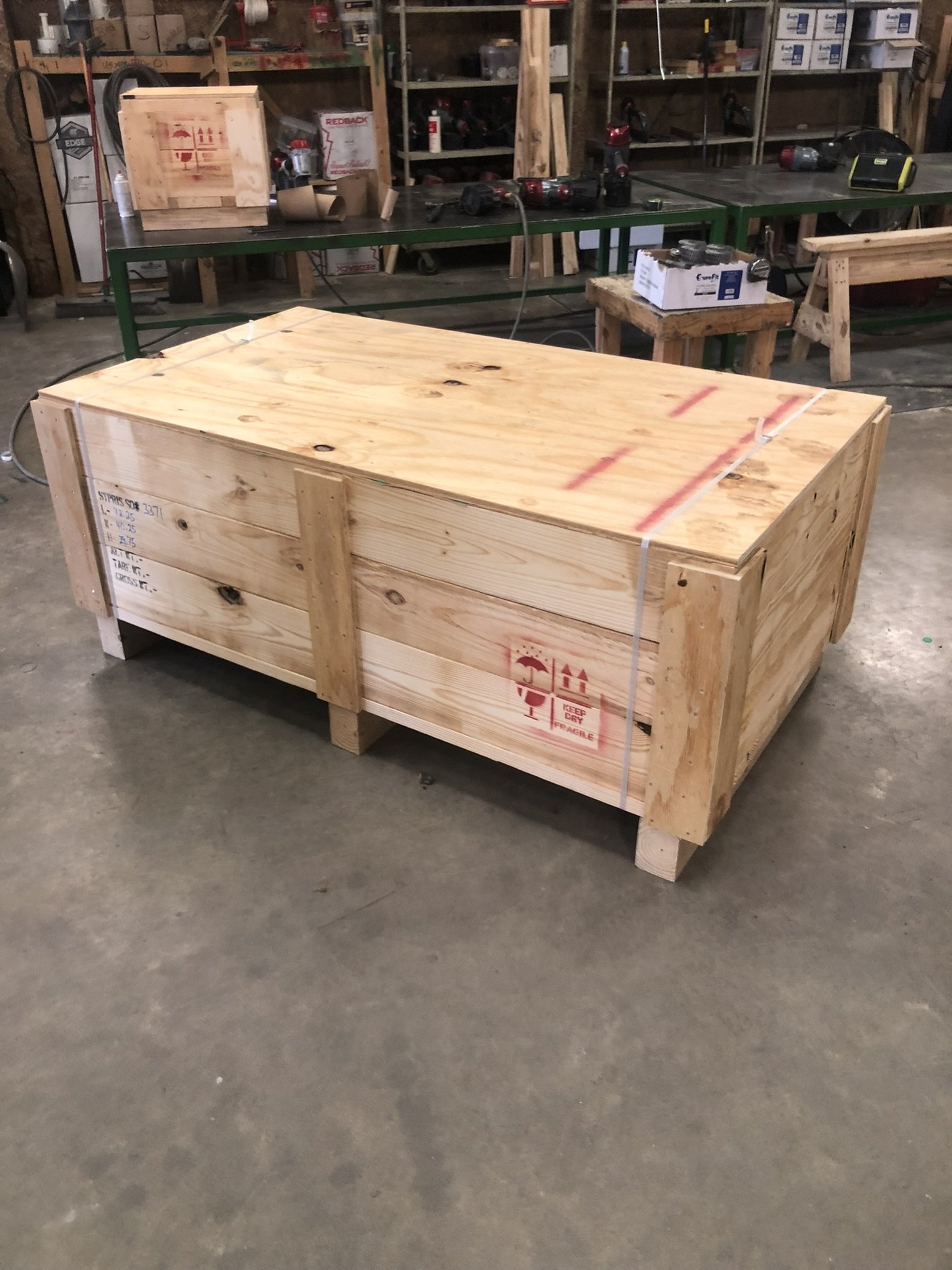 A large wooden crate in a workshop surrounded by workbenches and tools.