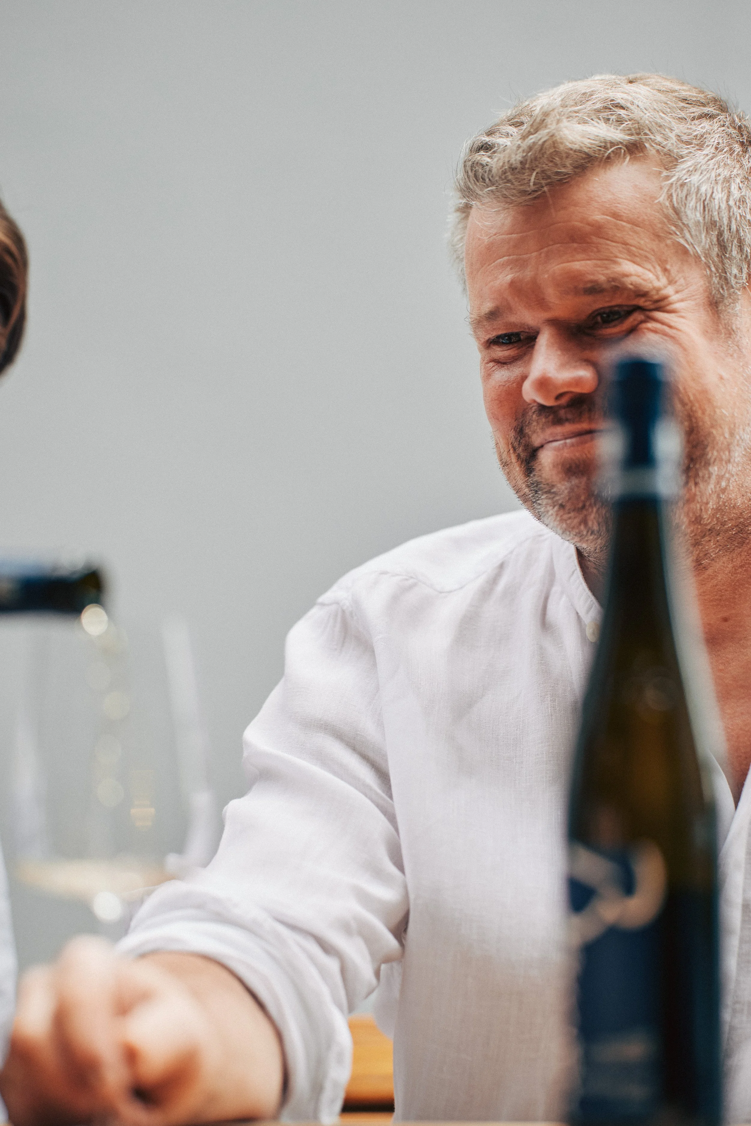 Winzer mit einer Flasche Wein in der Vinothek