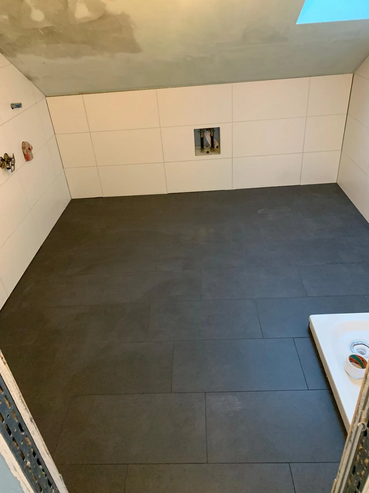 Fertig verlegte anthrazitfarbene Bodenfliesen in einem Badezimmer in Ulm