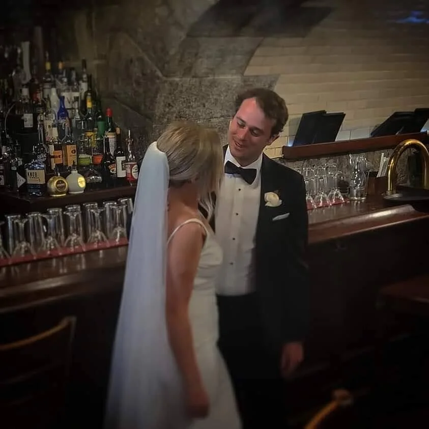 Bride and groom sharing a moment at a wooden bar during their reception