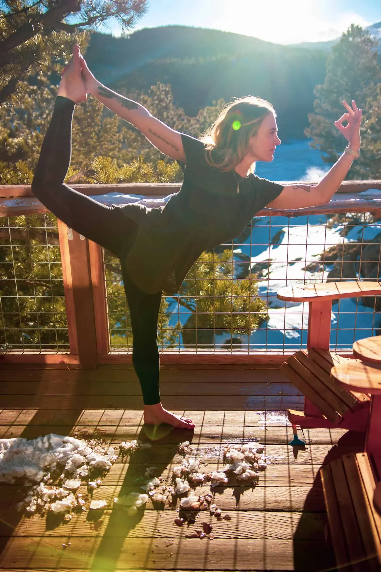 Woman practicing yoga in a dancer pose on a snowy mountain deck
