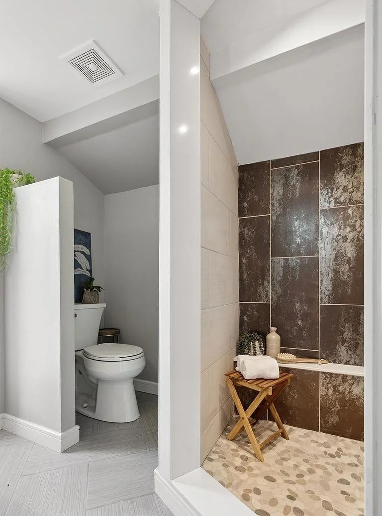 Bathroom remodel with a walk-in tile shower, large-format accent wall, pebble-stone shower floor and built-in bench.