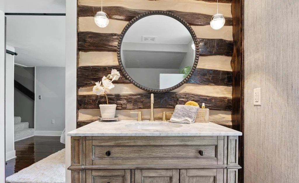 Bathroom vanity with a reclaimed barnwood accent wall, brass fixtures and pendant lights.