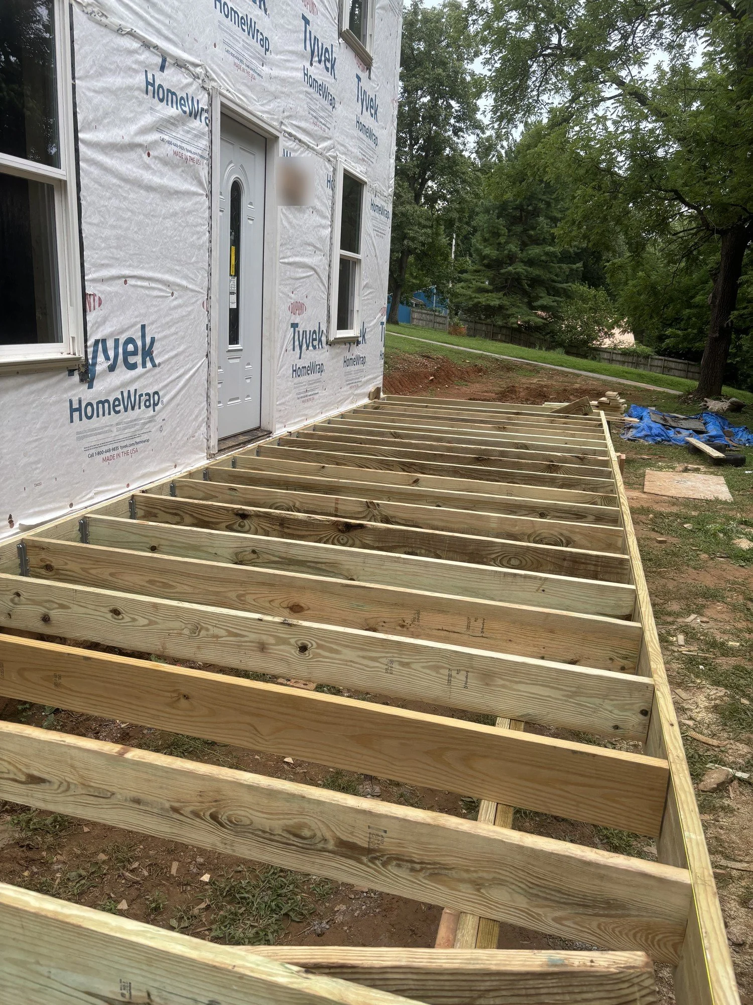 Large front porch deck framed with new pressure-treated joists, ready for decking and wide stairs.