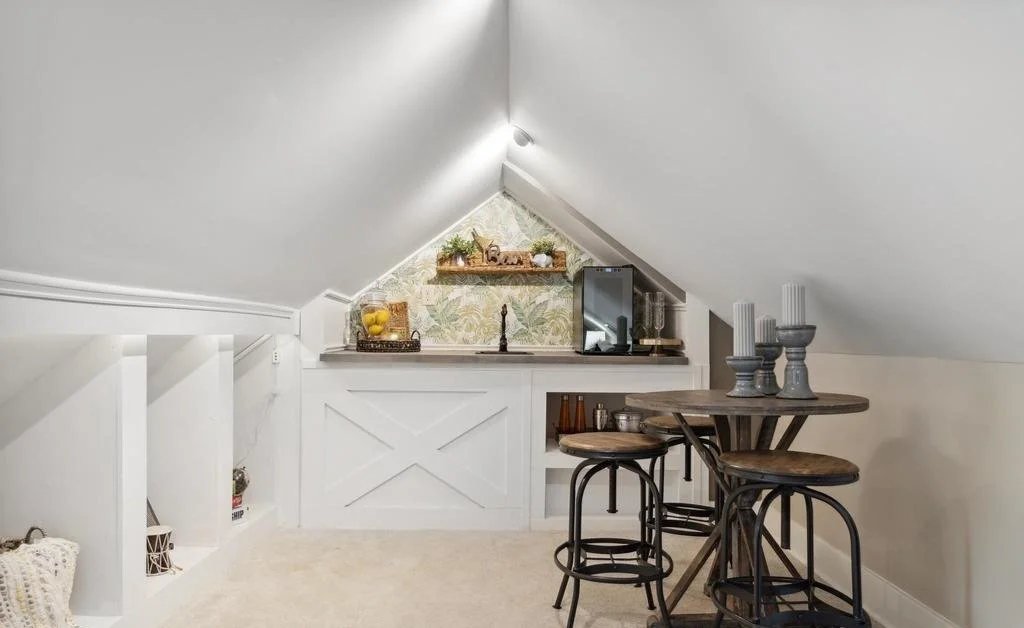 Attic wet bar tucked under the roofline, with custom X-panel cabinetry, a bar sink and a wine fridge.