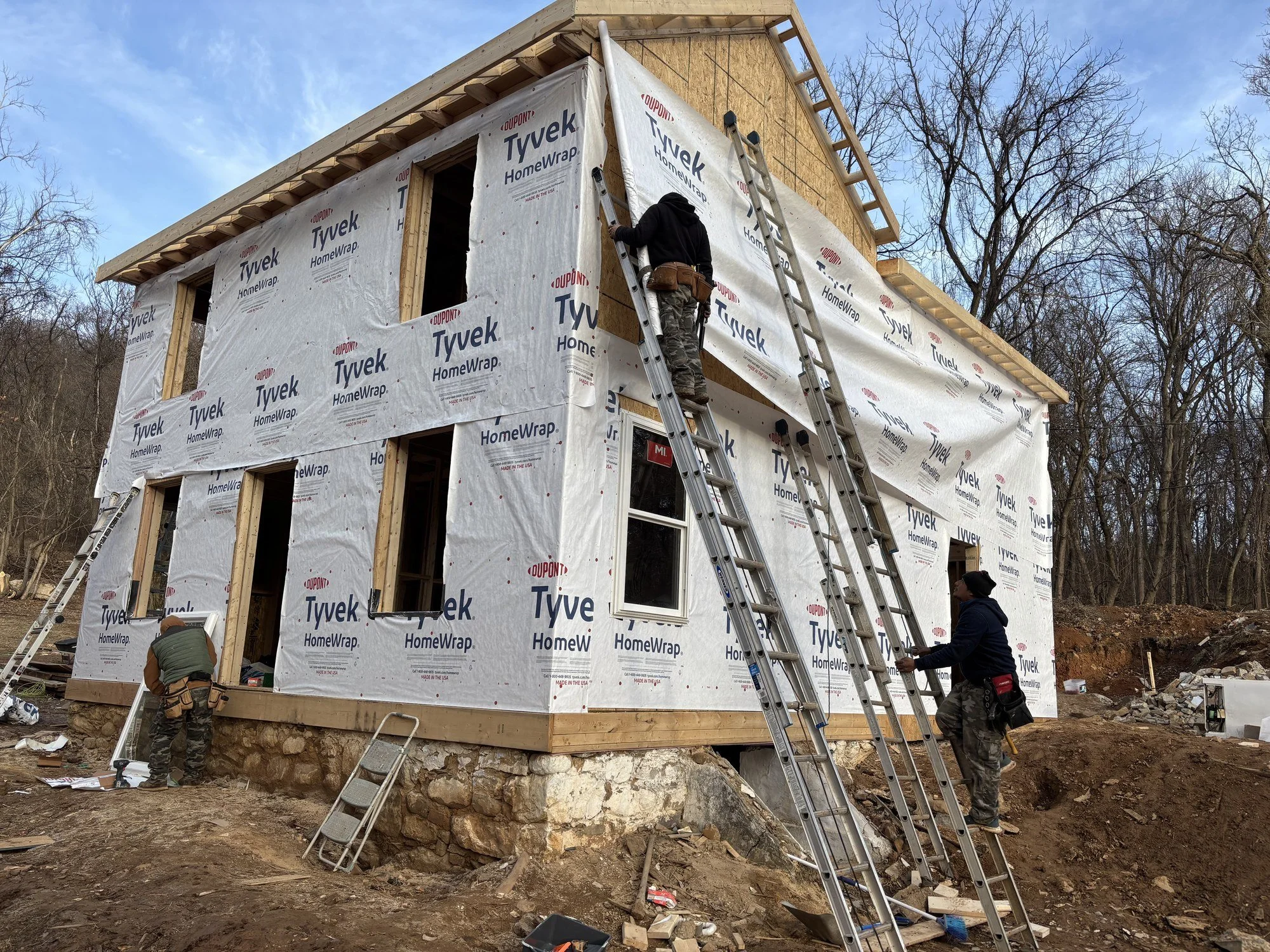Fully framed walls and roof on an older house, with the water barrier and new windows installed to seal it up tight.