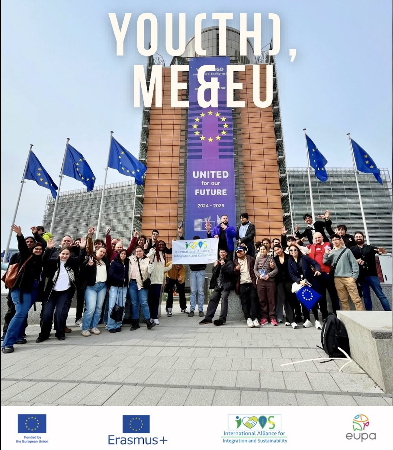 A group of diverse young people posing in front of a large building with European Union flags. They are holding a banner for the International Alliance for Integration and Sustainability, smiling and waving. The building displays a large vertical banner reading 'YOUTH, ME & EU' with the EU flag and the words 'United for our Future 2024-2029.'
