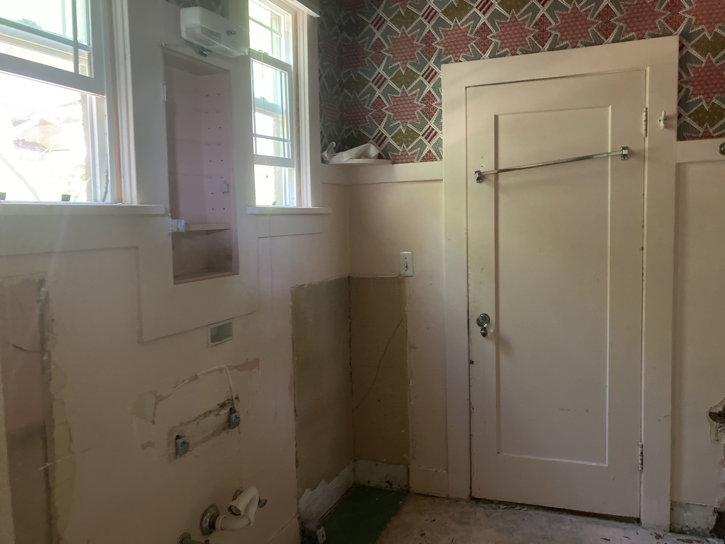 Empty room with window, partially built wall, and exposed plumbing.
