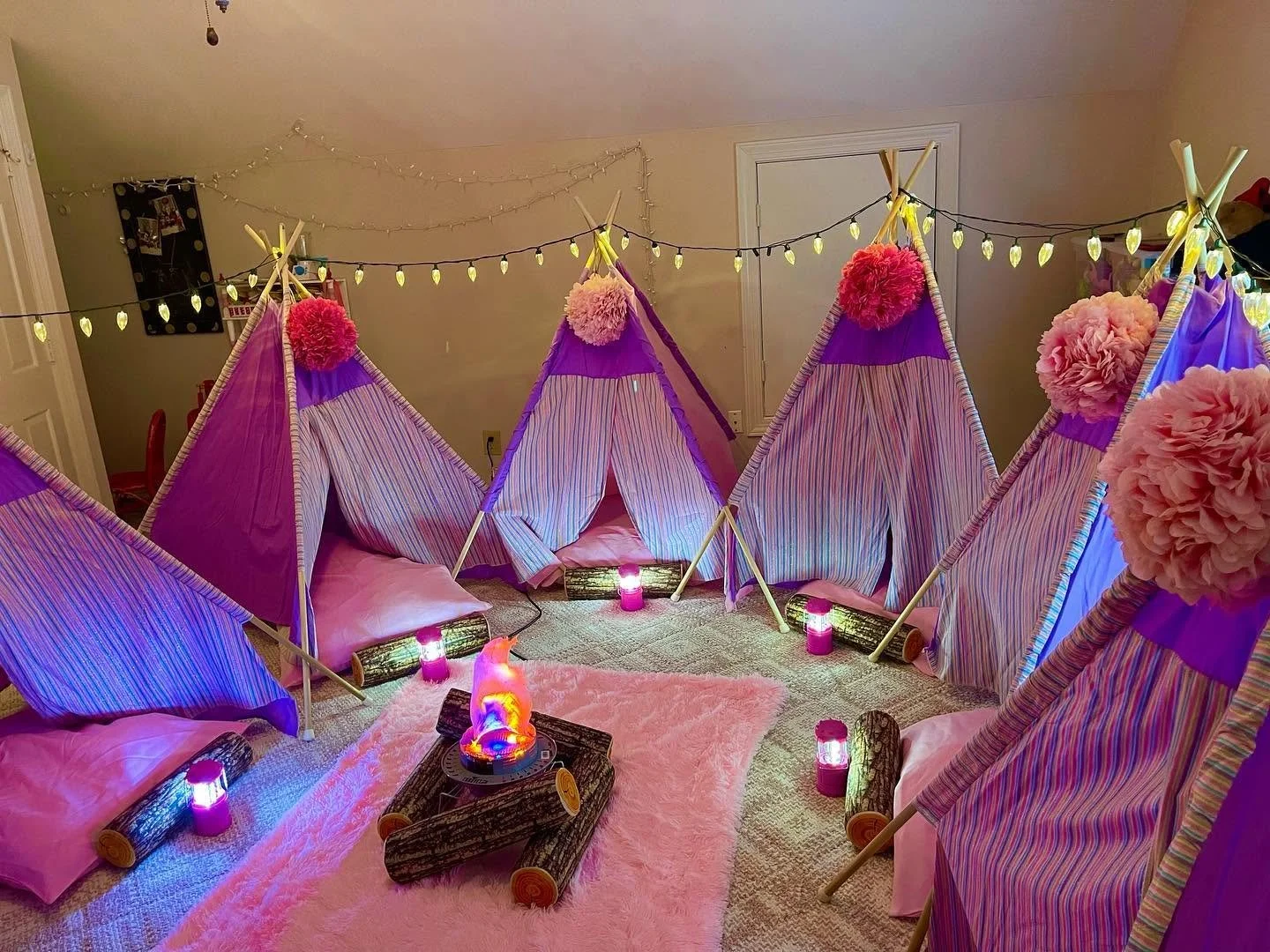 Teepee tents glowing around a campfire-inspired centerpiece