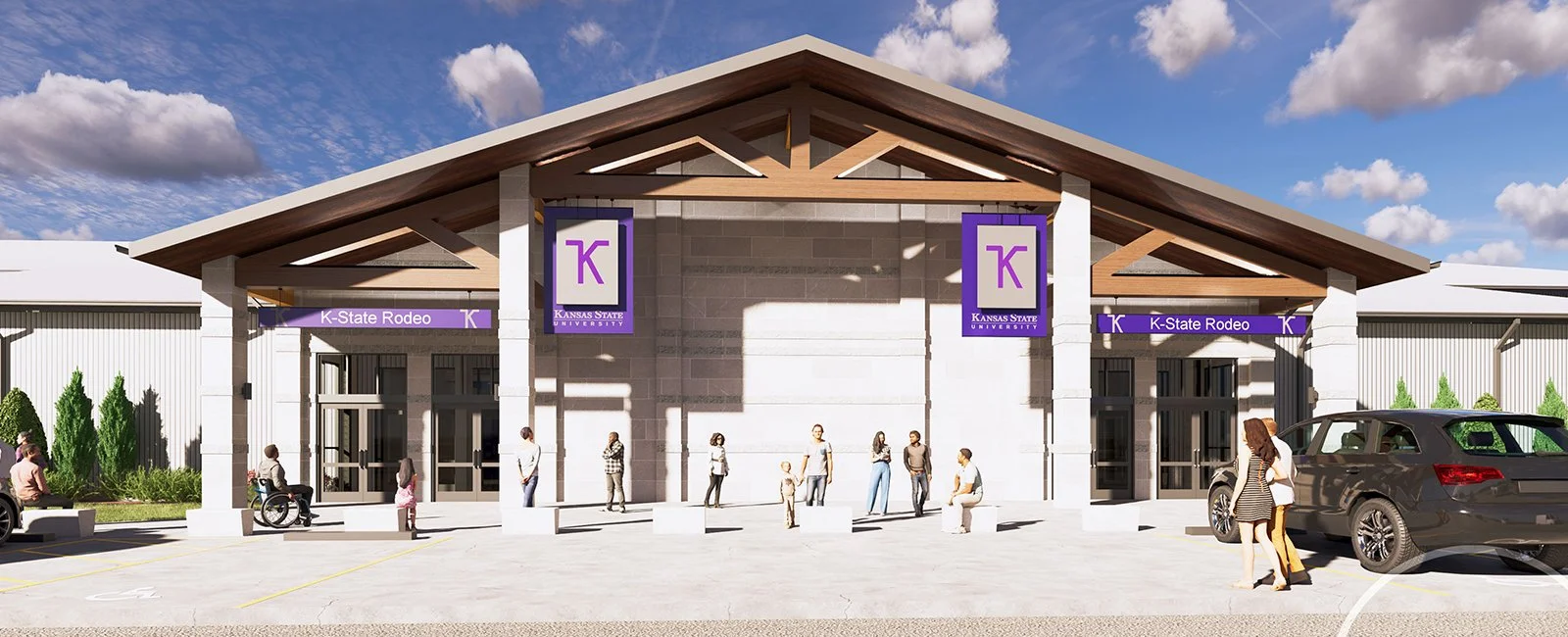 Front view of a building with a large entrance, two signs reading "K-State Rodeo," and a purple and white logo with a letter "K." Several people are standing and sitting outside, and cars are parked nearby.