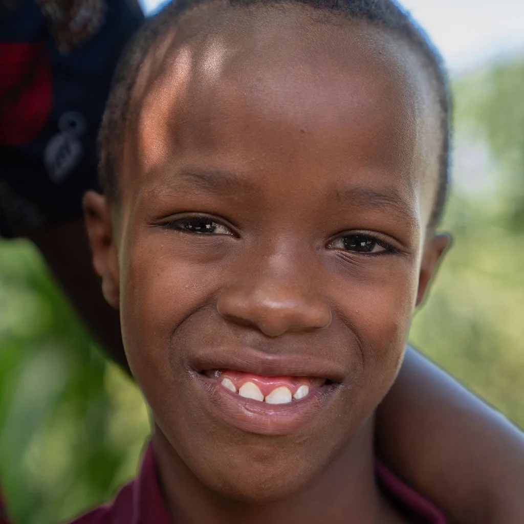 Close-up of a smiling young girl with missing teeth outdoors.