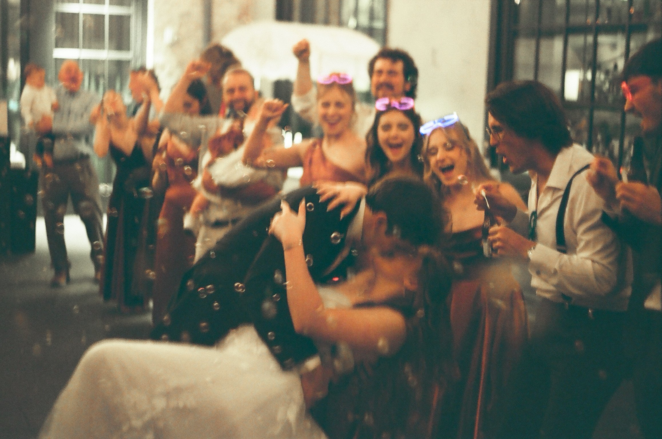 Group of people celebrating and dancing at an indoor party with some wearing glowing glasses.