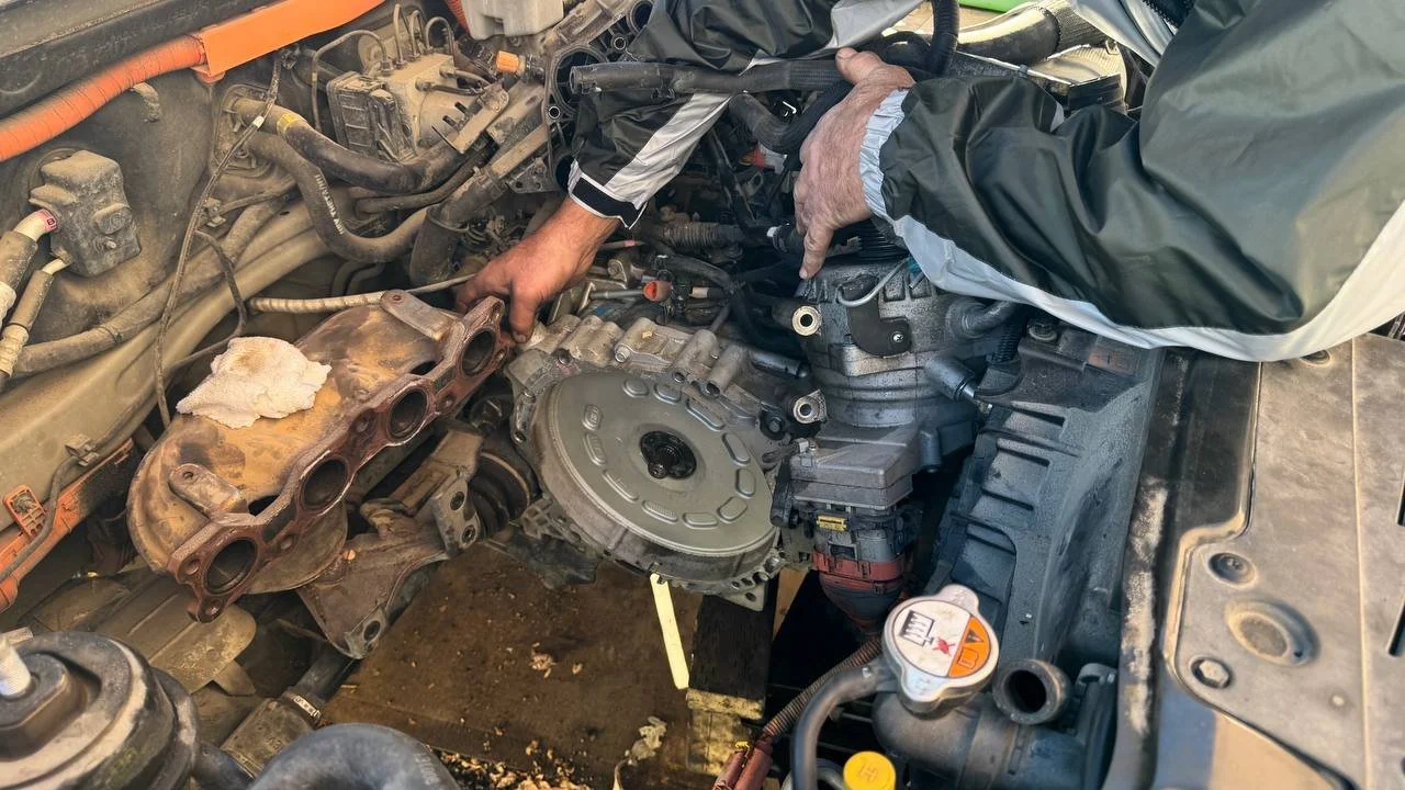 Exposed flywheel and engine bay during transmission replacement work