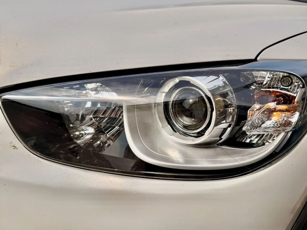 Close-up of a car's headlight on a silver vehicle.