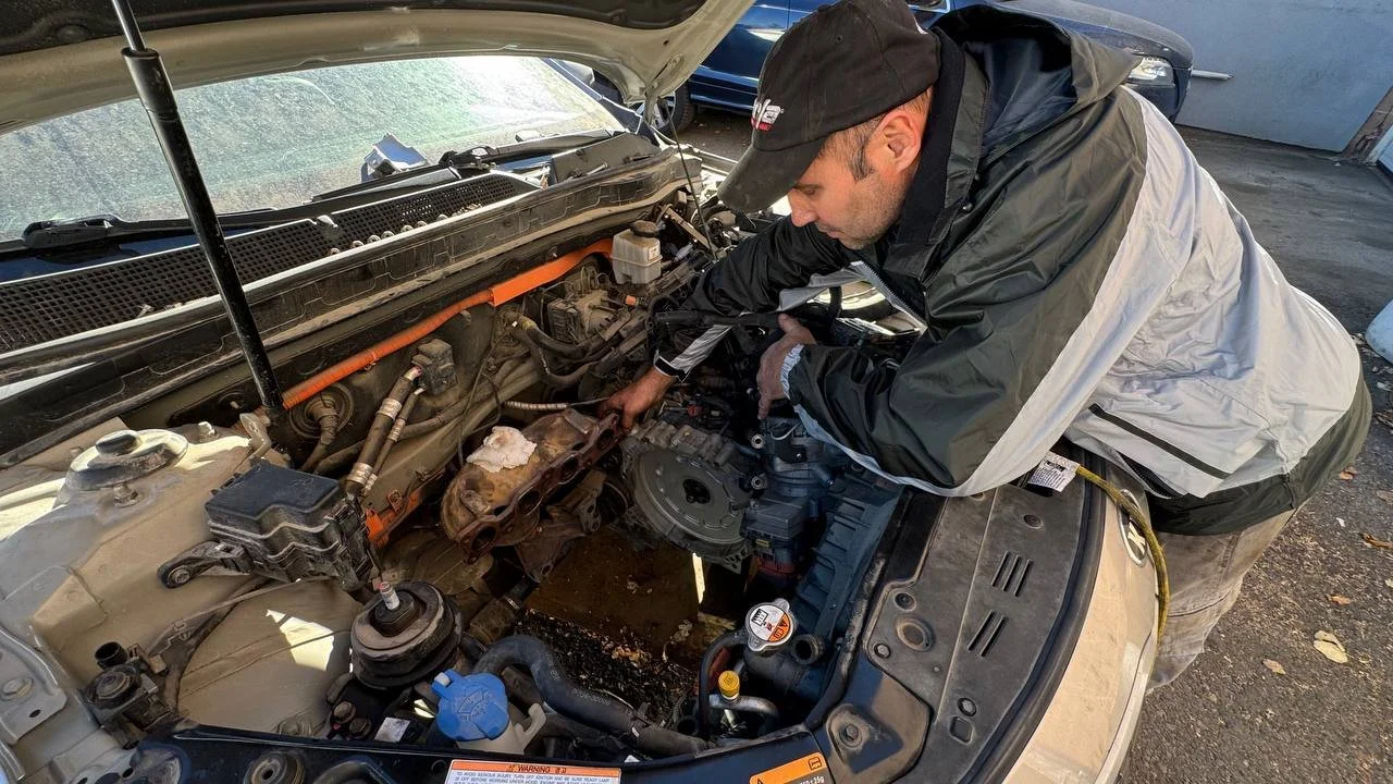 Mechanic working near a flywheel during transmission replacement