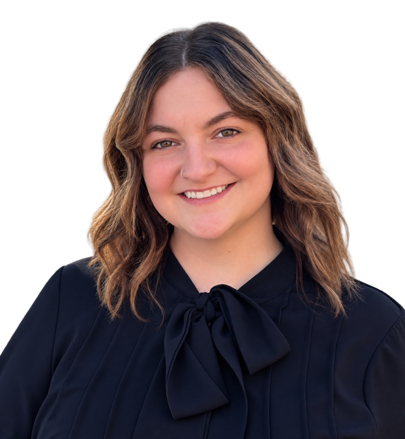 A young woman with shoulder-length wavy brown hair, wearing a black blouse with a bow tie at the collar, smiling with a neutral black background.