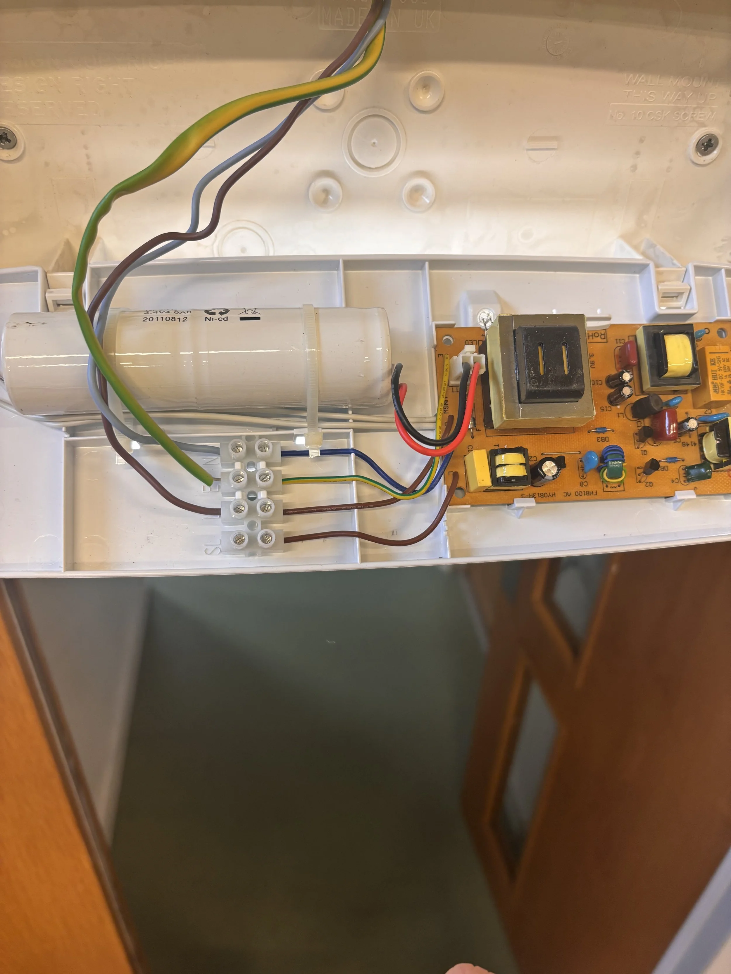 Inside an electrical device showing wiring, a capacitor, and a circuit board.