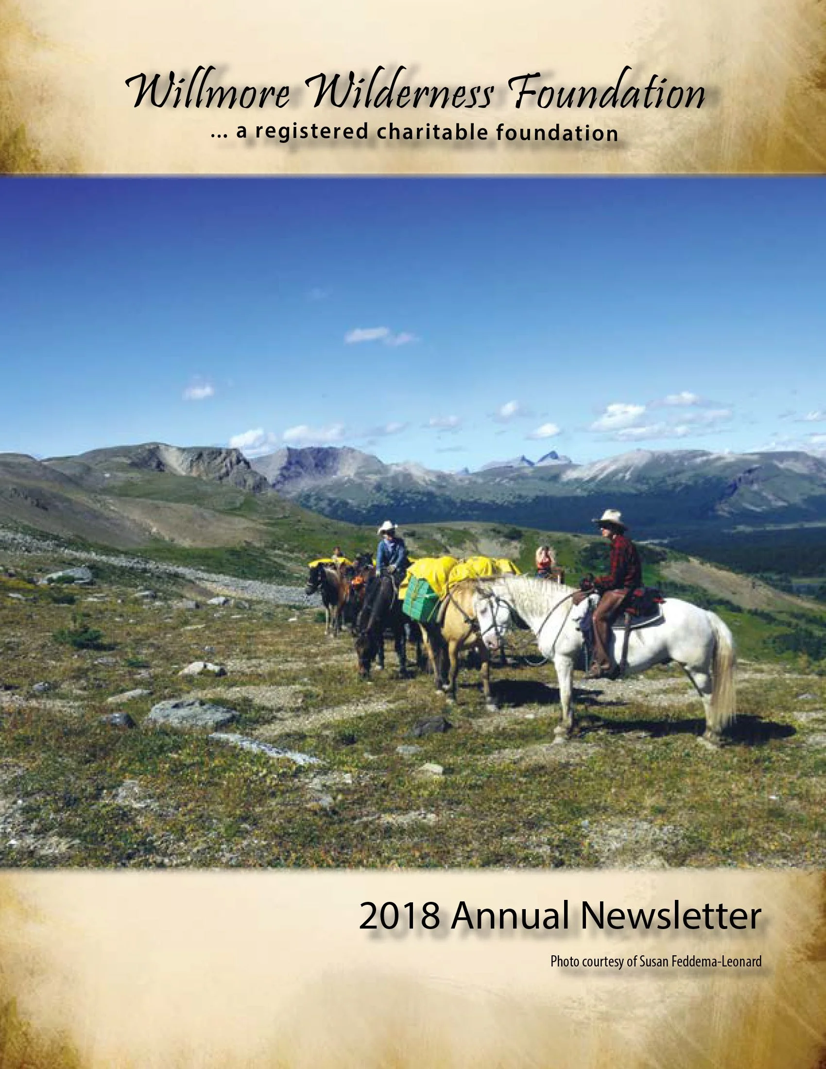 2018 Willmore Wilderness Foundation annual newsletter cover showing horseback riders with packhorses in an alpine mountain landscape