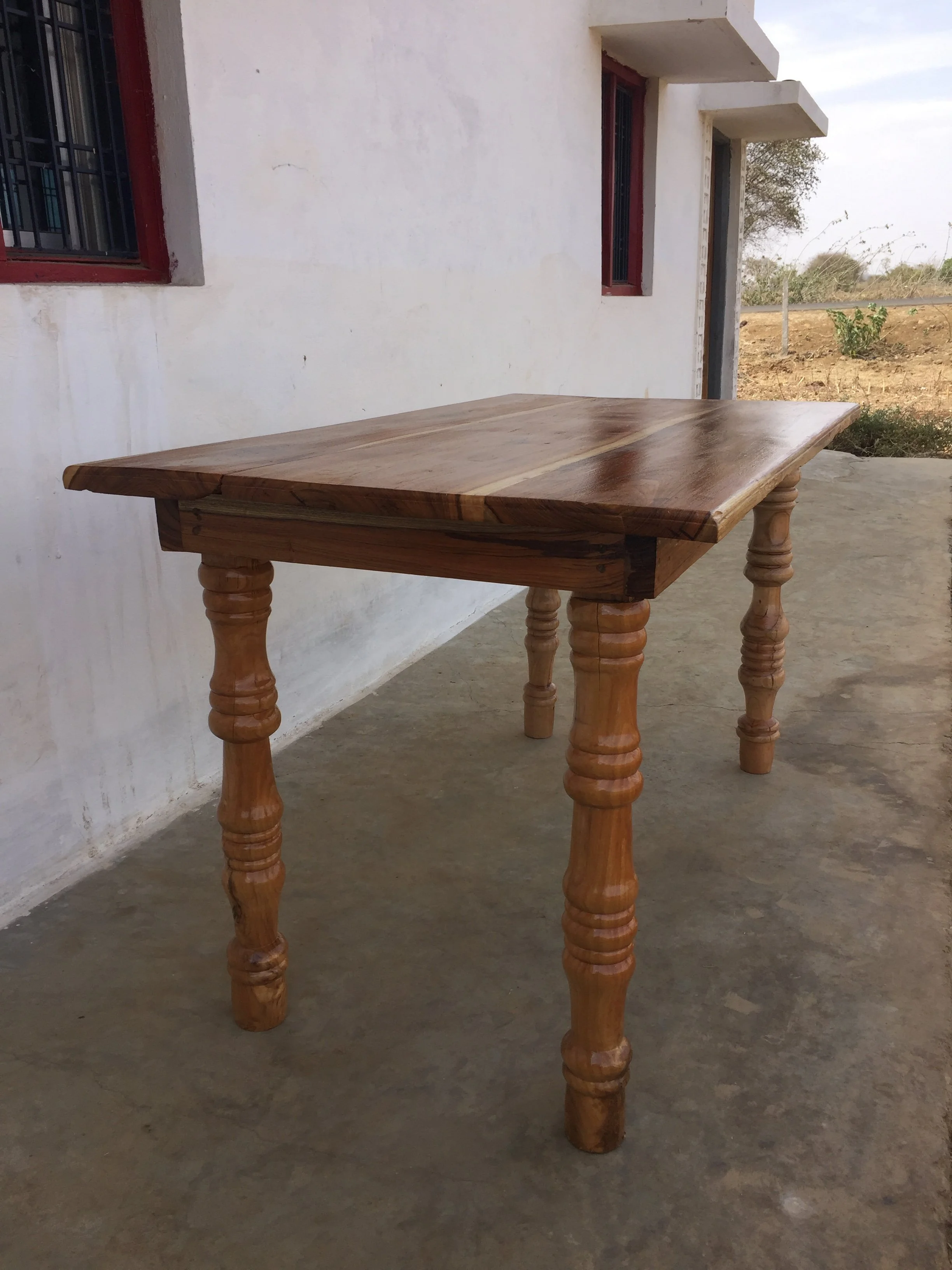 Solid teak table with turned legs. Table was built out in a rural area in India.