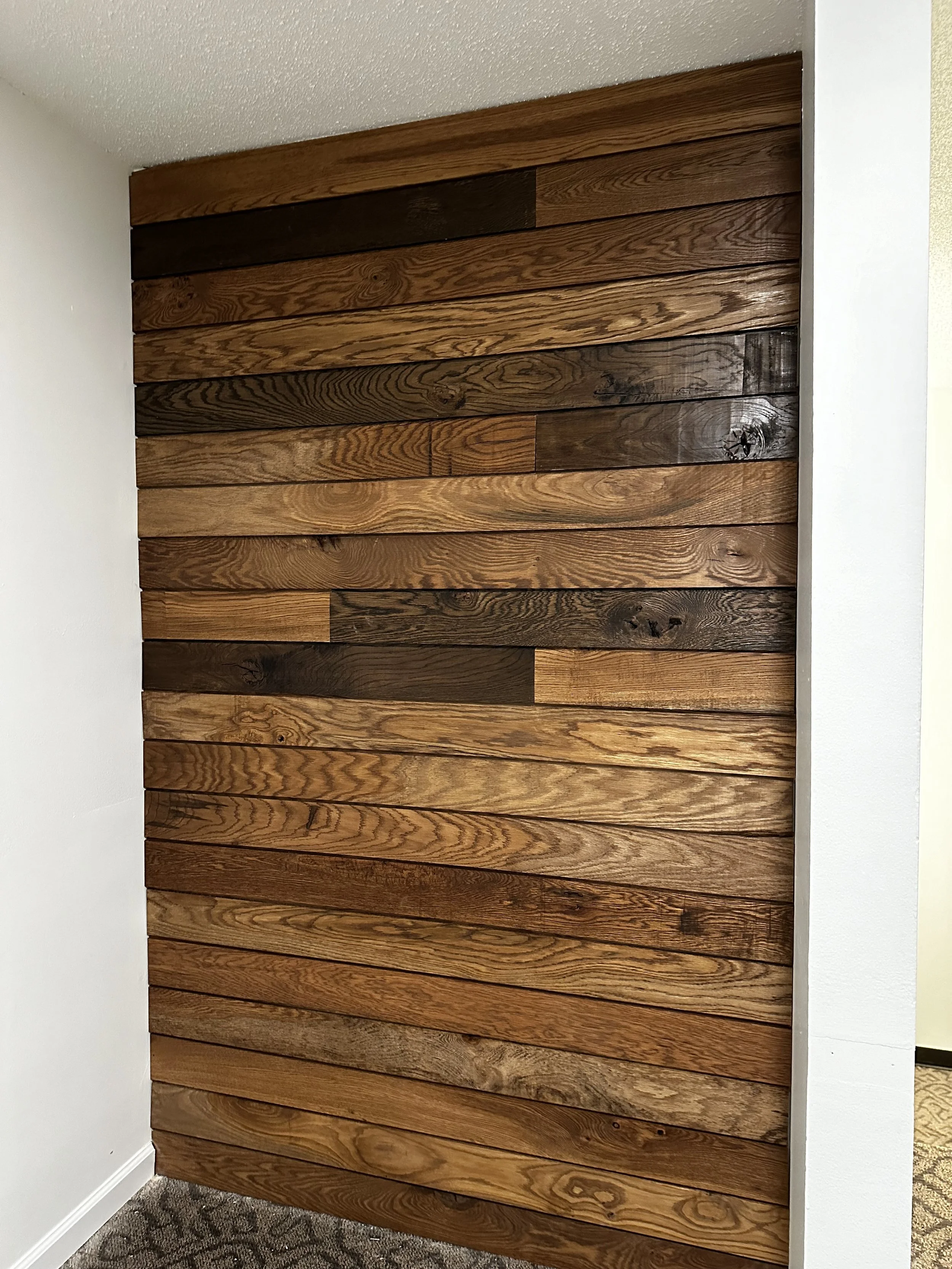 A wall decorated with horizontal wooden planks of various shades of brown, mounted in a staggered pattern.