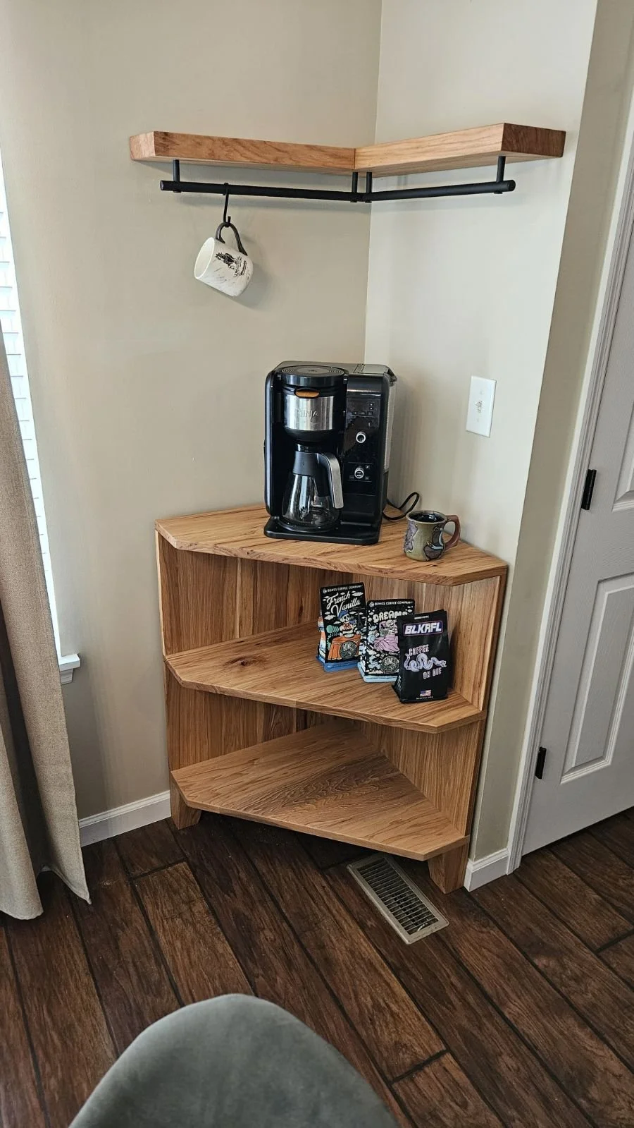 Wood corner shelf with coffee maker, mug, and books in a cozy kitchen corner.