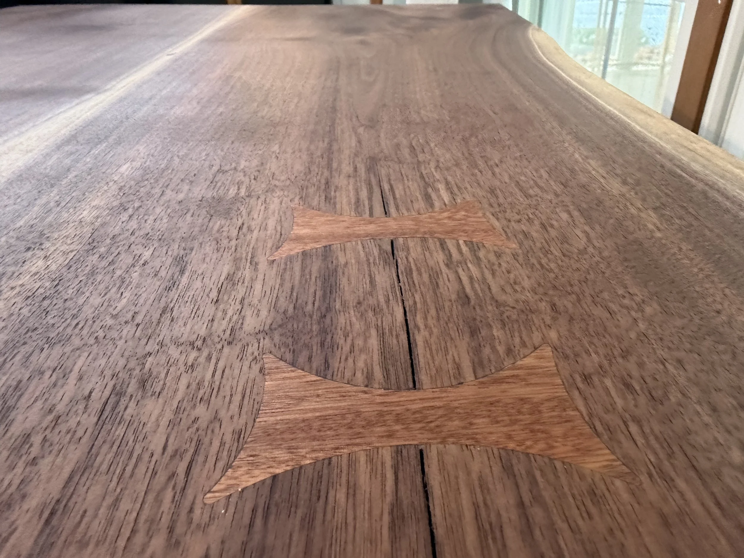 Close-up of a wooden table surface with a small wooden arrow at the center, pointing to the right.